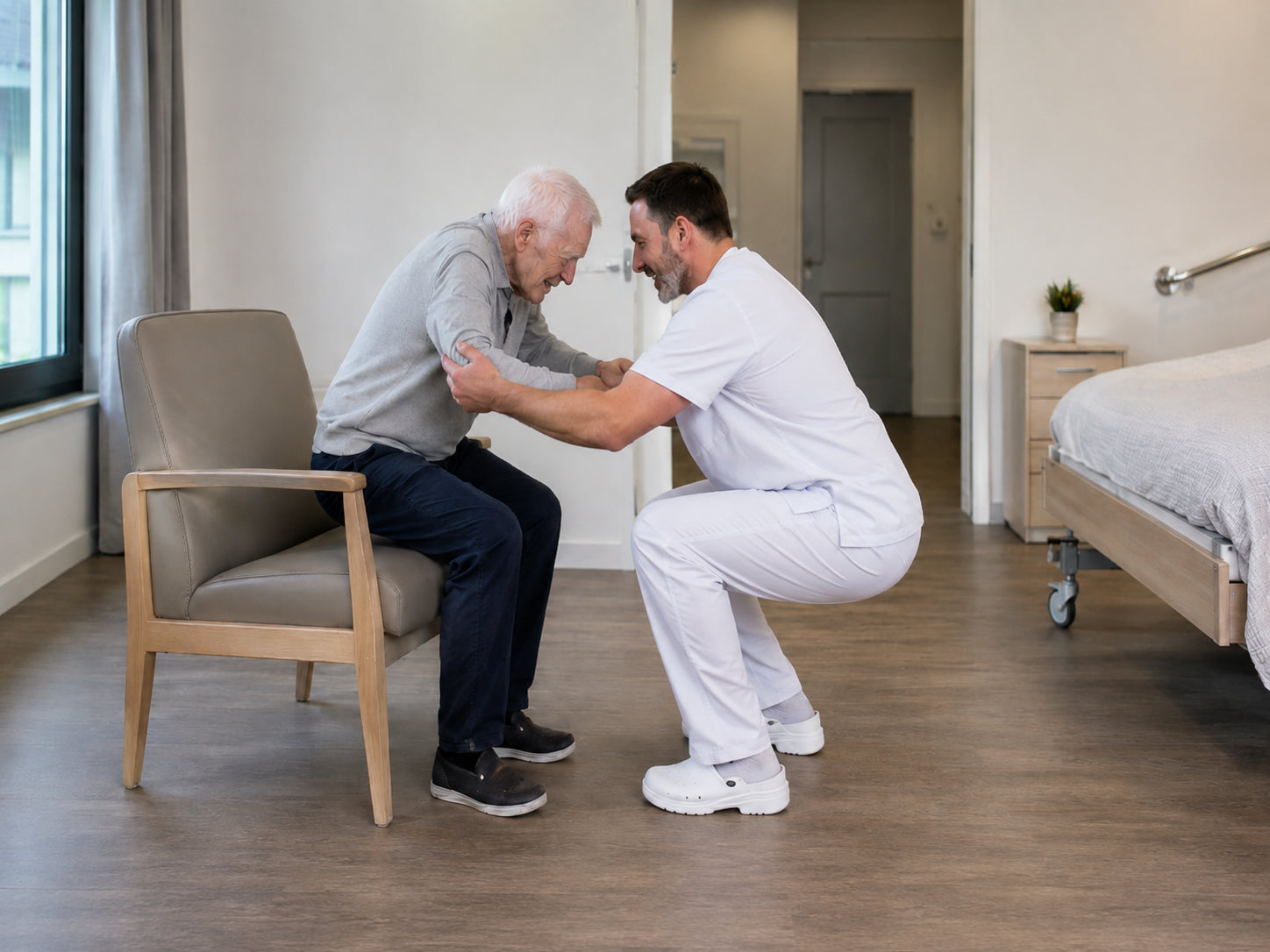 Un soignant accroupi accompagne le lever d'une personne âgée depuis un fauteuil, en fléchissant les jambes